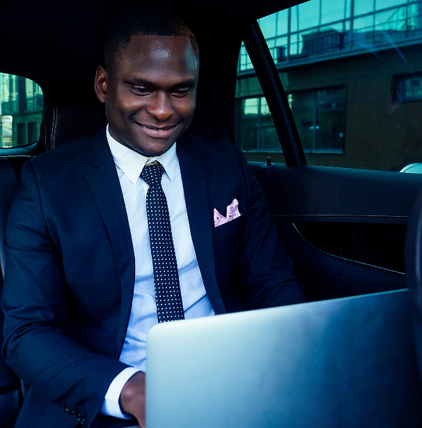 Man in suit typing on computer sitting in car