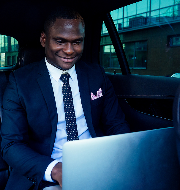 Man in suit typing on computer sitting in car